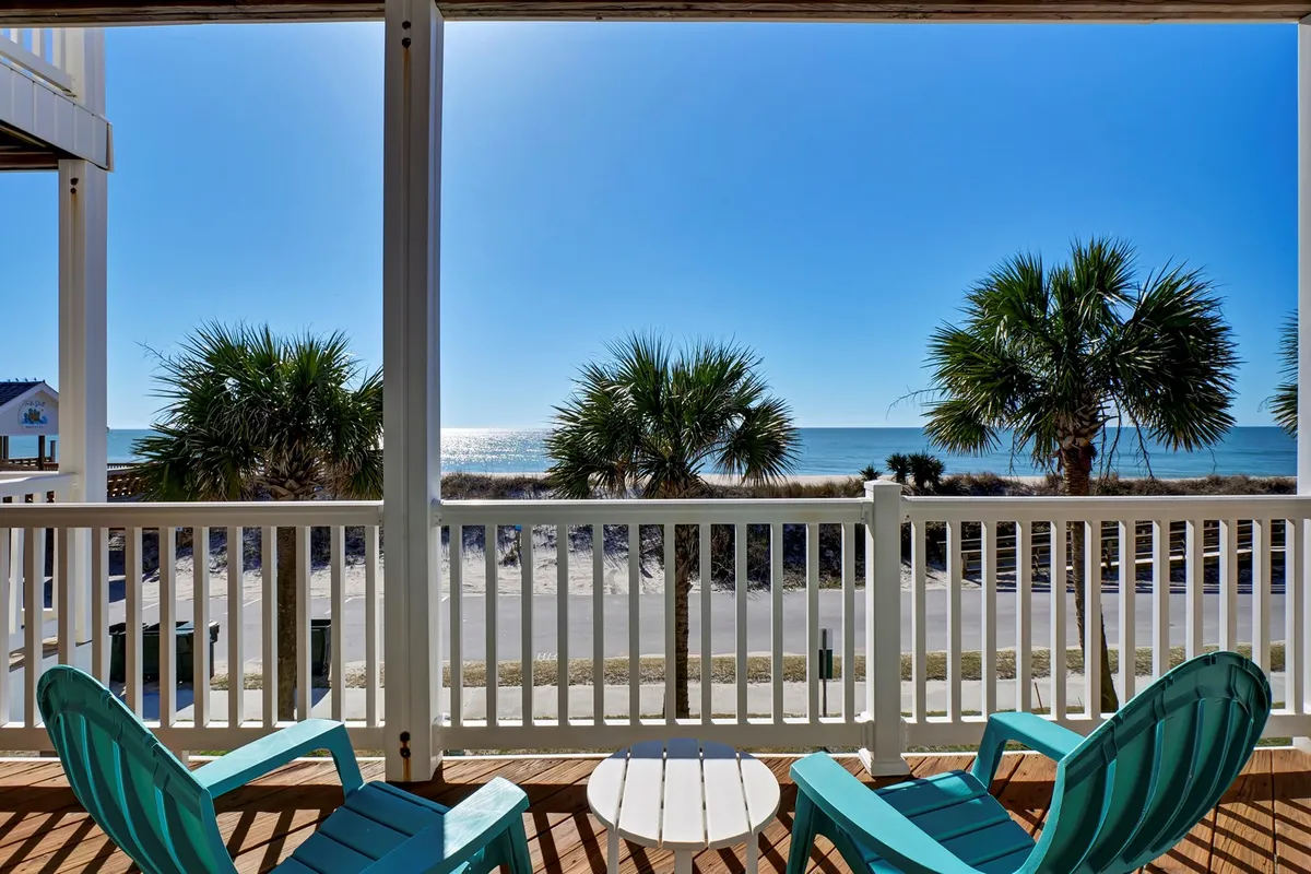 A serene deck with comfortable chairs looking out over palm trees and the ocean, ideal for relaxing, reading, or simply soaking in sunrise or sunset views. The mood is tranquil and private, emphasizing the connection to the outdoors.