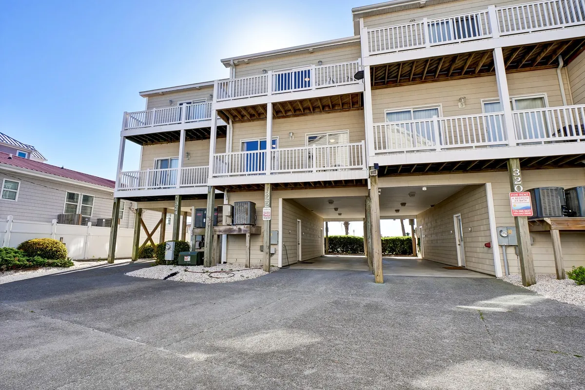 An exterior shot highlighting the building's balconies, the covered parking area below, and the inviting structure of Sea Star Village. The scene is bright and welcoming, demonstrating both convenience and the architectural appeal of the property.